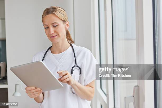 nurse or doctor using digital tablet - caucasian doctor and nurse using tablet computer stock-fotos und bilder