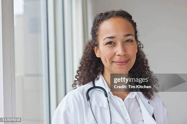 doctor in lab coat smiling, portrait - médecin content photos et images de collection