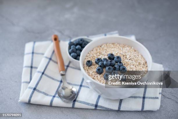 homemade oatmeal with blueberries and strawberries in bowl on gray concrete background. healthy breakfast. - blue bowl stock-fotos und bilder