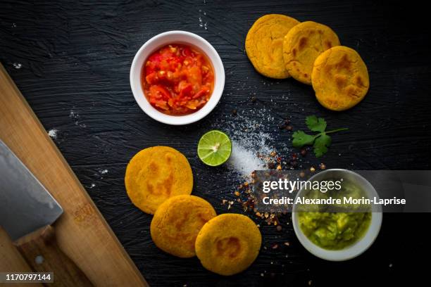 ingredients and preparation of typical colombian food: arepas with two sauces, guacamole and hogao. - arepas stockfoto's en -beelden