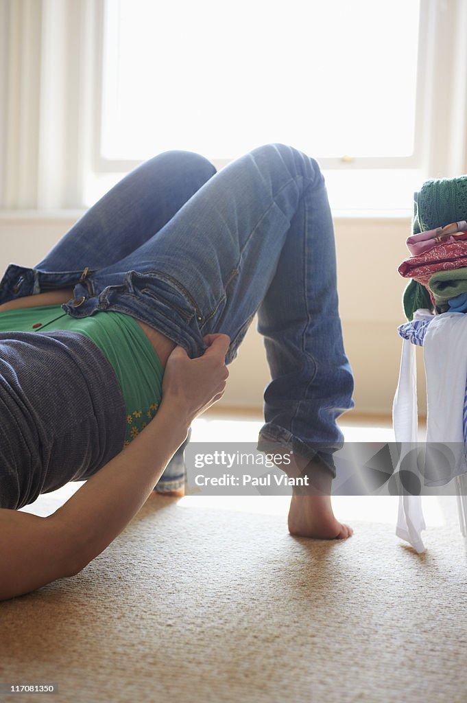 Young woman putting on jeans