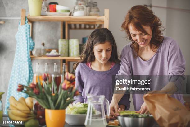 mother and daughter packing a lunch box in the kitchen - mother daughter cooking stock pictures, royalty-free photos & images