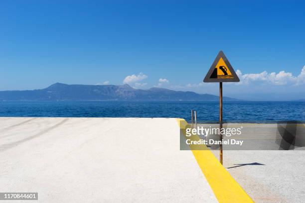 road sign warning drivers not to drive over the edge of the harbor into the sea - safe harbor stock pictures, royalty-free photos & images