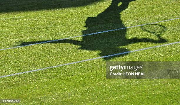 The shadow of US player John Isner is seen as he plays with French player Nicolas Mahut during the men's single at the Wimbledon Tennis Championships...