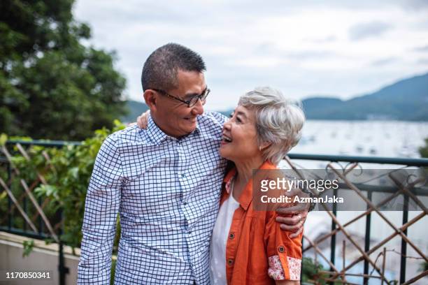 embracing senior chinese couple outdoors in hong kong - asian senior couple stock pictures, royalty-free photos & images