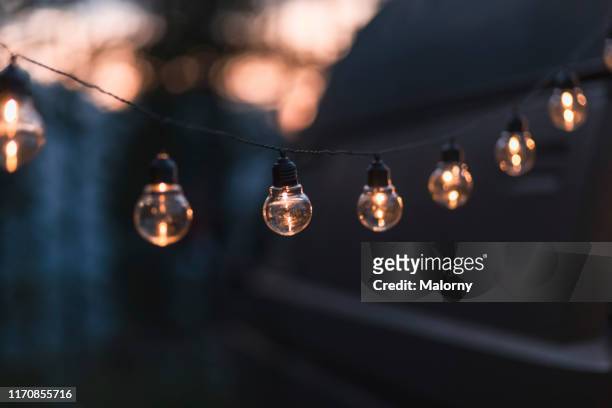 close-up of illuminated light string - summer party lights stock-fotos und bilder