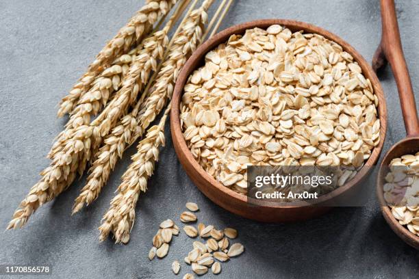 oat flakes or rolled oats in wooden bowl - oat stock pictures, royalty-free photos & images