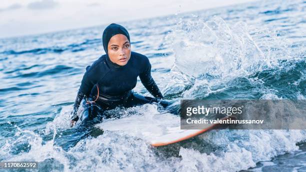 vrouwelijke surfer met hijab in zee - religion of sports tribeca tv festival stockfoto's en -beelden
