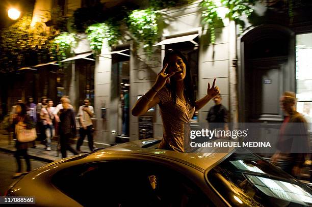 Woman dances with her upper body protruding from out of the sunroof of a car on June 21, 2011 in Paris, during the 30th annual music event, "La Fete...