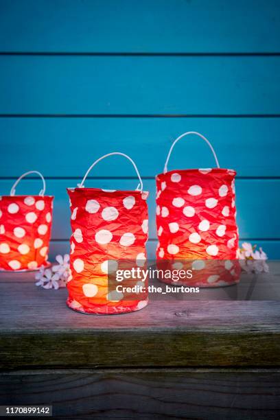 still life of dotted red paper lanterns for party decoration in front of blue wooden wall in the evening - lanterns stock-fotos und bilder