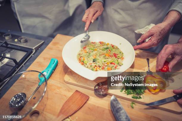 senior woman preparing risotto. close up shot - risoto stock pictures, royalty-free photos & images