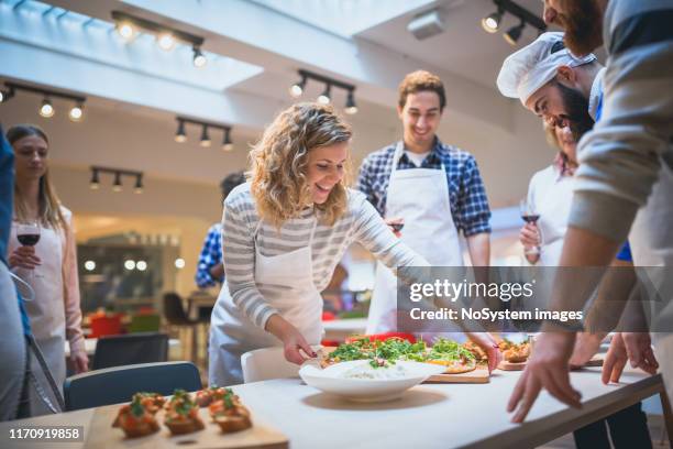 die teilnehmer des kochkurses servieren ihre zubereiteten speisen für chefkoch - live ereignis stock-fotos und bilder