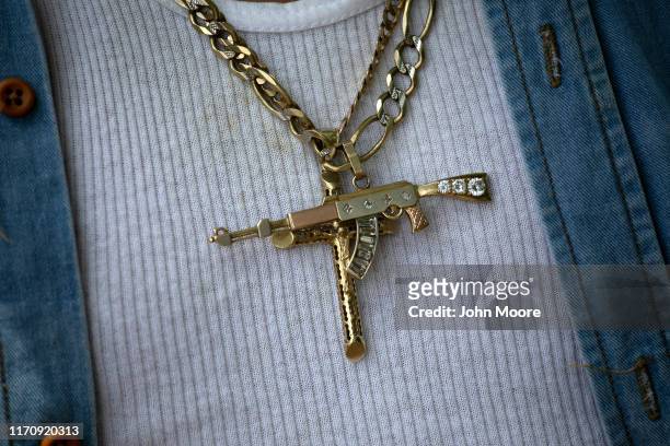 Man wears a diamond-encrusted AK-47 pendant after his weapon was seized at a temporary checkpoint run by Guatemalan border police and U.S. Advisors...