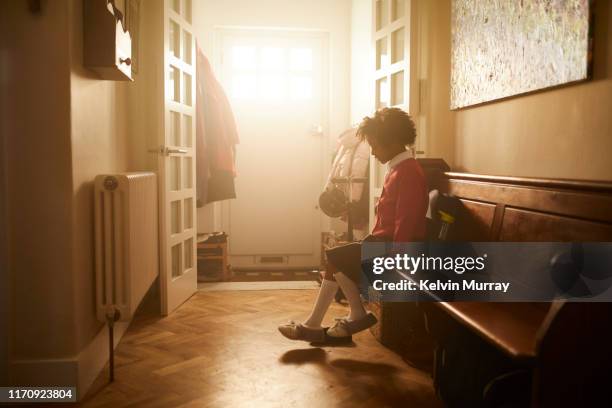 A school girl putting on shoes in the hallway