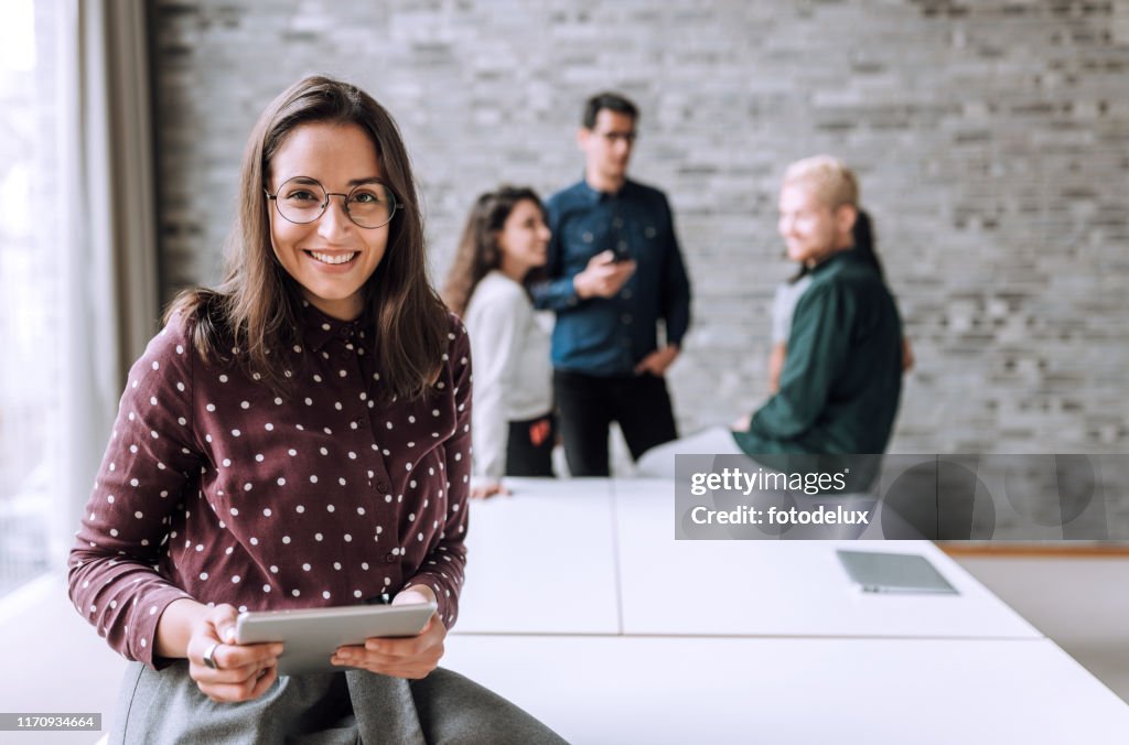 Lächelnde Frau mit einem Tisch t im Büro