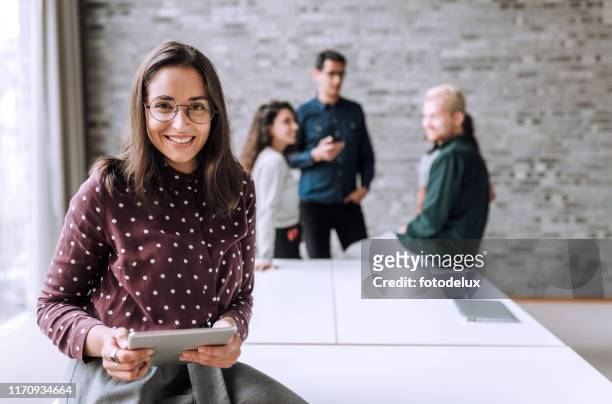 donna sorridente con un tavolo t in ufficio - abbigliamento casual foto e immagini stock