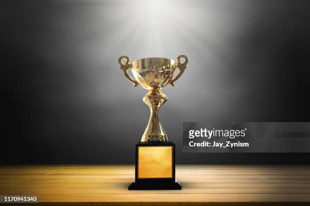 golden trophy on table against black background - trophy award stock pictures, royalty-free photos & images