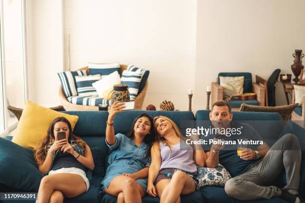 family watching tv on sofa at home - tv internet phone stock pictures, royalty-free photos & images