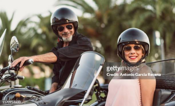 couple in sidecar bike loking at camera, senior man and mid adult woman traveling - motorcycle side car stock pictures, royalty-free photos & images