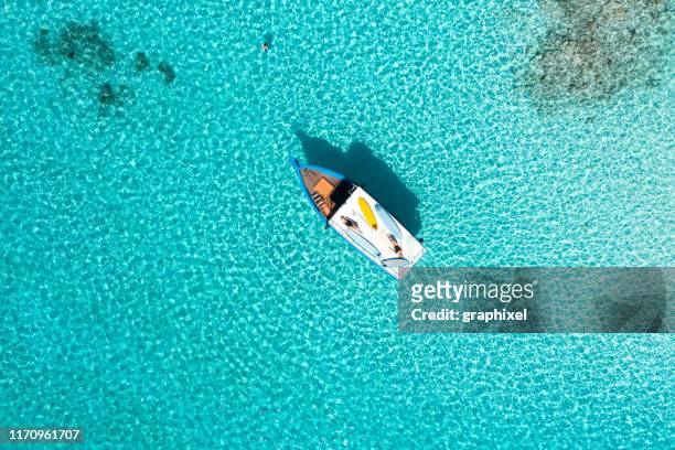 two women with surfing boards on boat in blue ocean - maldives boat stock pictures, royalty-free photos & images