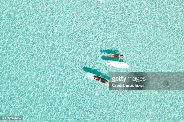 two women on paddle board in blue ocean - água parada imagens e fotografias de stock