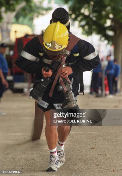 Des pompiers court avec des tuyaux, le 08 juillet 2000 sur le Champ de Mars à Paris, lors d'une épreuve comptant pour les 6èmes jeux mondiaux des...