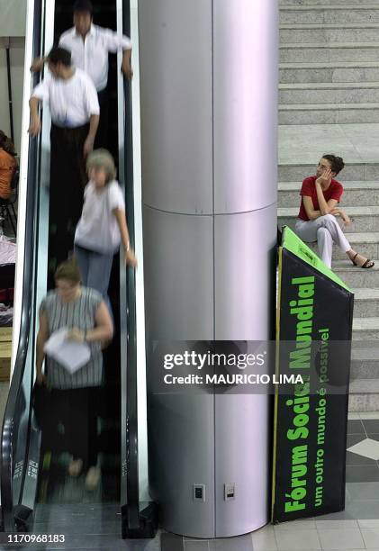 Woman looks at people going down on an escalator in the entrance of the Social Worlds Forum in Porto Alegre, Brazil, 24 January 2001. Una mujer...