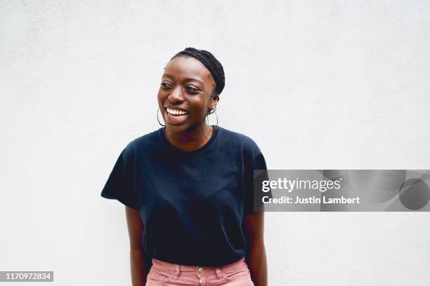 confident woman laughing and looking off camera shot against white wall - stylish man looking away stock-fotos und bilder