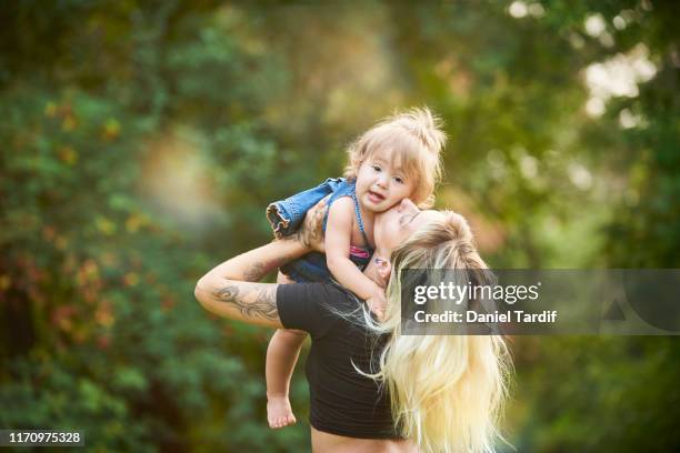 young mother lifting infant daughter in air outdoors. - pierced nose stock pictures, royalty-free photos & images