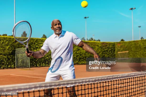 ein hübscher schwarzer tennisspieler mittleren alters auf dem platz - sports training drill stock-fotos und bilder