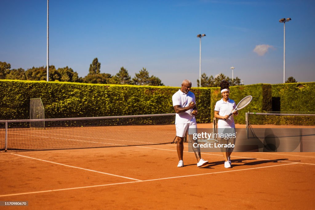 A beautiful black female tennis player on the court with her father and coach