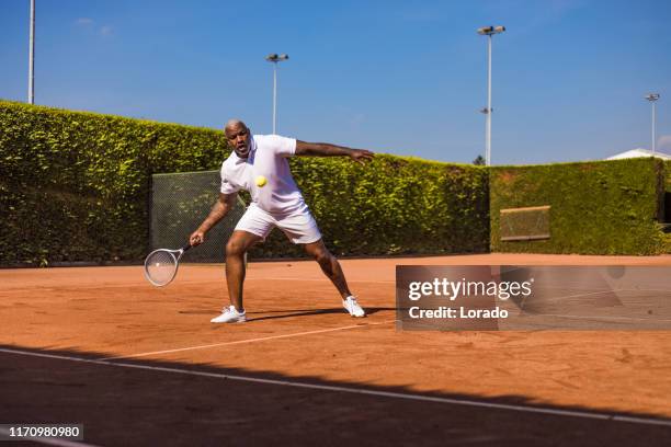 a handsome black middle aged male tennis player on the court - amateur tennis man stock pictures, royalty-free photos & images