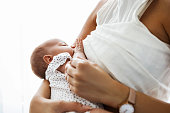 Mother breastfeeding and holding newborn baby