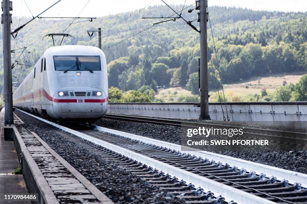 An ICE high speed train of Germany's public rail operator Deutsche Bahn drives on rail tracks painted in white color on September 18, 2019 in...