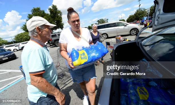 Sheila Guerra loads cases of bottled water into her car at a Wal-Mart Super Store in preparation for Hurricane Dorian on August 29, 2019 in Orlando,...