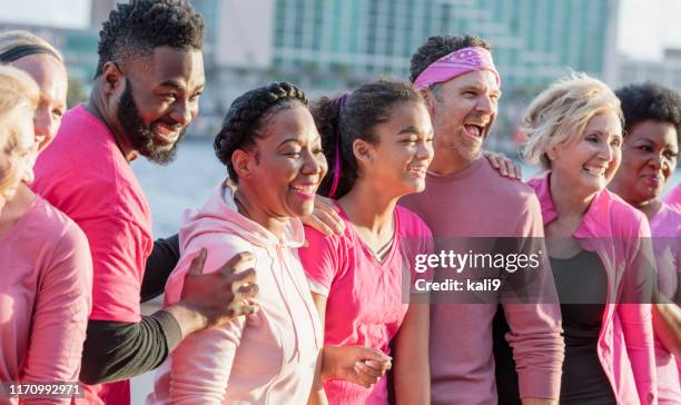 groupe d'hommes et de femmes dans le rose, au rassemblement de cancer du sein - femme dans un groupe dhommes photos et images de collection