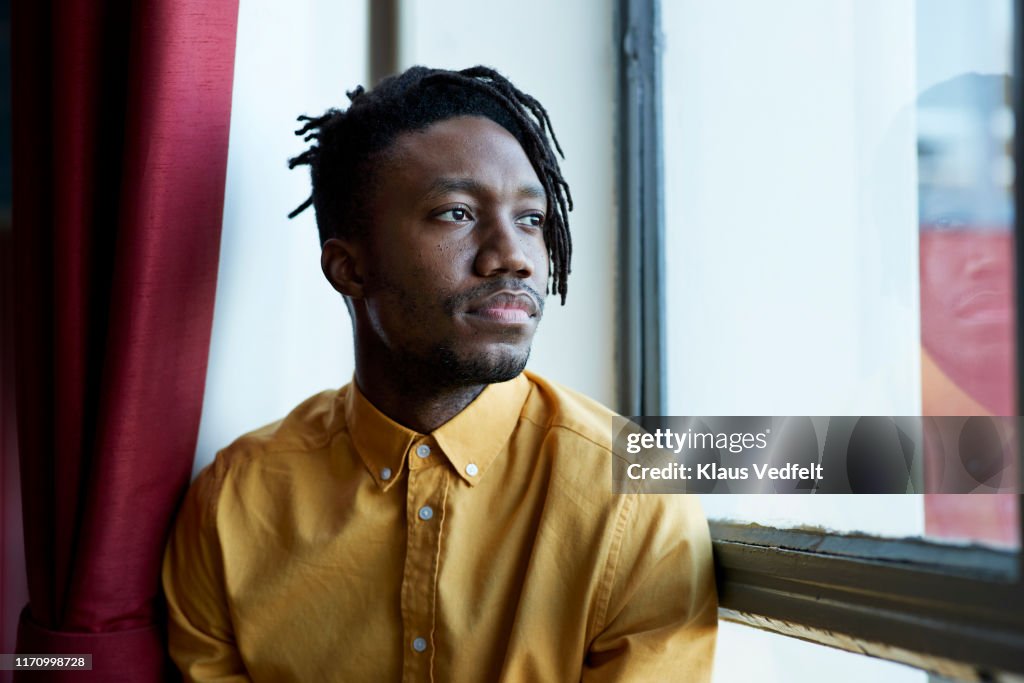 Thoughtful young man looking through window