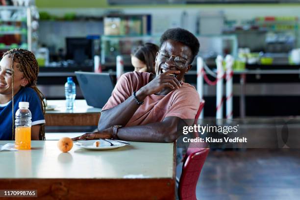 cheerful man laughing by female friend at table - college canteen bildbanksfoton och bilder