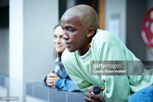 young man looking away while leaning on wall - college of fashion design stock pictures, royalty-free photos & images