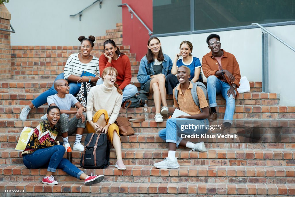Smiling young university students sitting on steps