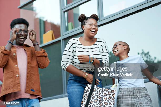 cheerful young friends against window at college - male student wearing glasses with friends stockfoto's en -beelden