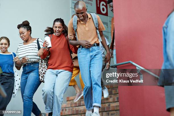 cheerful young friends rushing down on staircase - four people walking away stock pictures, royalty-free photos & images