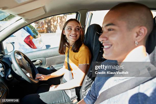 smiling young friends sitting in car on sunny day - front passenger seat stock-fotos und bilder