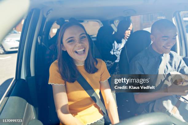 happy young woman sitting with friends in car - 3 guy friends road trip photos et images de collection