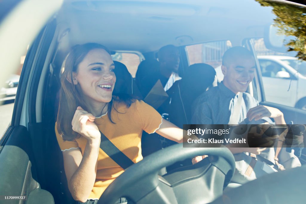 Happy young woman dancing with friends in car