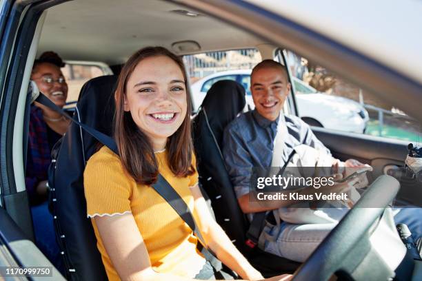 smiling young woman sitting with friends in car - car pooling stock pictures, royalty-free photos & images