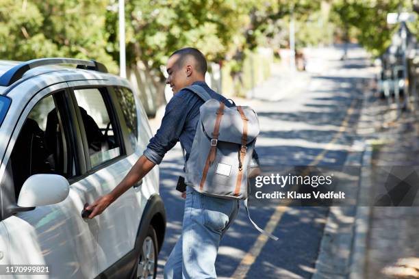 male student opening car door on roadside - car door stock pictures, royalty-free photos & images