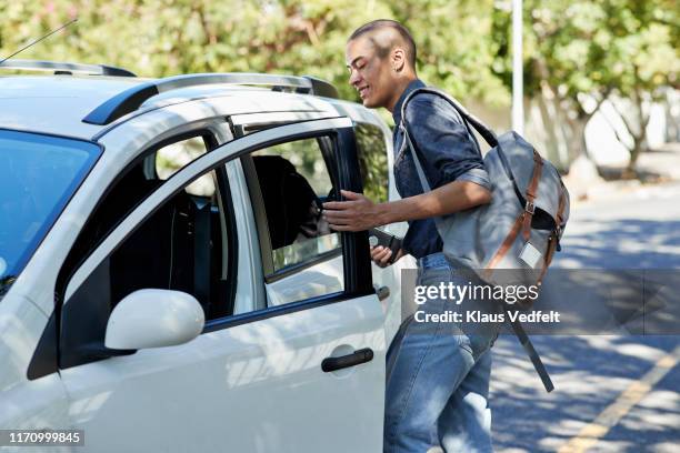 male student entering car on roadside - auto stehend stock-fotos und bilder