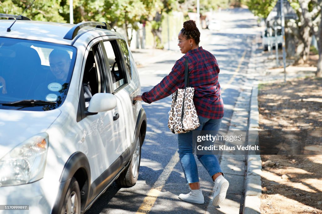 Female student opening car door on roadside