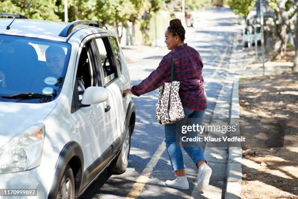 female student opening car door on roadside - bildörr bildbanksfoton och bilder